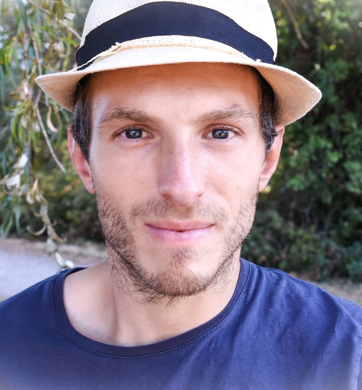 À propos Yohann Vidal avec un chapeau dans la nature entouré de végétaux bien verts.